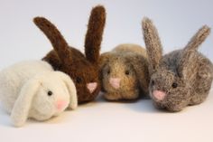 three small stuffed animals sitting next to each other on a white surface with one bunny and the other rabbit