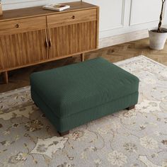 a green footstool sitting on top of a rug in front of a dresser