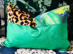 a green pillow sitting on top of a blue chair next to a leopard print wallpaper