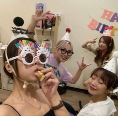 three young women wearing party hats and holding up their fingers in front of the camera