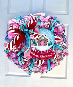 a christmas wreath hanging on the front door with candy canes and a gingerbread house