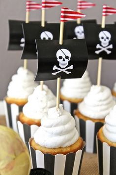 cupcakes with white frosting and pirate flags on them are sitting on a table