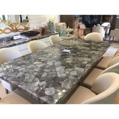 a dining room table with white chairs and a large black marble slab on the top