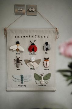 an insect chart hanging on a wall next to a pink flower and two small vases