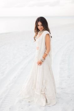 a woman standing in the snow wearing a white dress and holding her hand on her hip