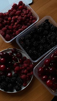 three plastic containers filled with cherries on top of a wooden table next to a laptop