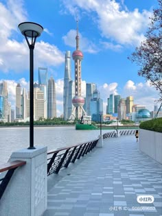 the city skyline is seen from across the water with a bench and lamp post in front