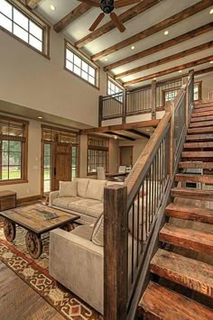 a living room filled with lots of furniture and wooden stairs leading up to the second floor