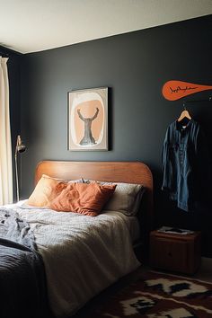 a bed sitting in a bedroom next to a window with an orange pillow on top of it