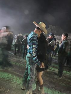 two people standing next to each other in front of a group of people wearing cowboy hats