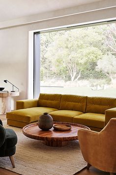 a living room filled with furniture next to a large glass window overlooking a forest area