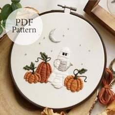 a cross stitch pattern with a ghost and pumpkins on the hoop next to it