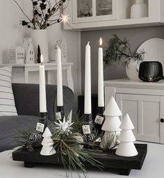 white candles are sitting on a tray in front of a christmas tree and other decorations