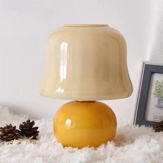 a yellow table lamp sitting on top of a white rug next to a pine cone