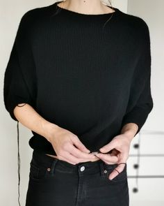 a woman in black shirt and jeans holding her phone