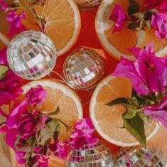 oranges and pink flowers are arranged around disco balls