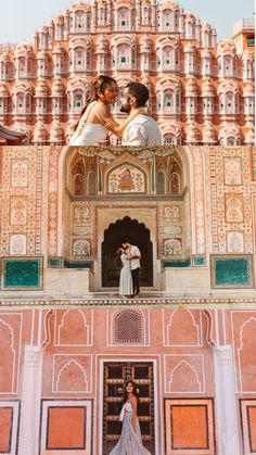 the bride and groom are posing for pictures in front of an ornate building with pink walls