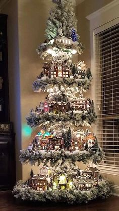 a christmas tree is decorated with lights and houses in the shape of snowflakes