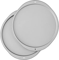 two round metal trays sitting side by side on top of each other in front of a white background