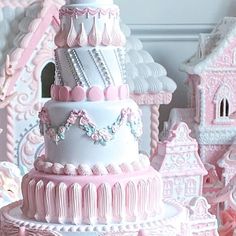 a large pink and white cake sitting on top of a table next to other cakes