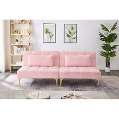 a pink couch sitting on top of a wooden floor next to a potted plant