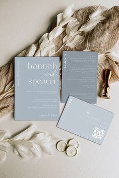 the wedding stationery is laid out next to some feathers