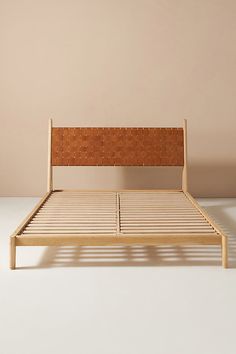 the bed frame is made from wood and has a woven headboard on one end