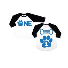 two white and black shirts with blue paw prints on the front, one has a dog's name printed on it