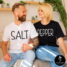 Custom made to order SALT or PEPPER unisex short sleeve couples t-shirt.  (Each shirt is purchased separately.) Photo shows Matte Black Design on Salt Shirt and Matte White Design on the Pepper Shirt. ADULT:  These soft and comfy shirts are high quality unisex shirts.  The unisex adult shirts are a slim semi-fitted cut.  So they are more slim and fitted for a man.  If you want a looser fit I suggest a size up.  They would run pretty true to a loose fit in womens sizing.  I have included the sizing charts by the manufacturers above in the photos.  Please take your favorite comfy shirt, lay it on a flat surface and compare the measurements of your favorite fitting shirt to the manufacturer's specs. KIDS:  These soft and comfy bodysuits and tees run pretty true to size to a little on the smal Black Cotton Couples T-shirt, Black Cotton T-shirt For Couples, Couples Cotton Tops With Letter Print, Family Matching Short Sleeve T-shirt With Custom Text, Couples Cotton T-shirt Gift, Couples Cotton T-shirt For Gift, White Short Sleeve Couples T-shirt, White Matching Couples T-shirt, Couples White Short Sleeve T-shirt