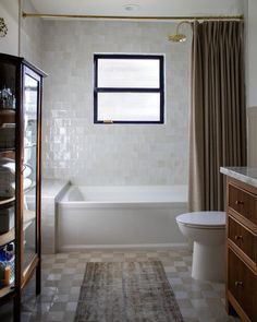 a bathroom with a toilet, sink and bathtub next to a window in the wall