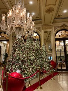 a large christmas tree in the middle of a room with chandeliers hanging from it