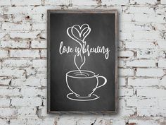 a chalkboard sign that says love is believing with a cup of coffee in the shape of a heart