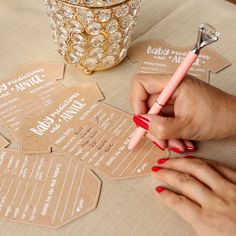 a person writing on some brown paper with a pink pen in their left hand and a gold container behind them