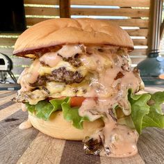 a cheeseburger with meat, lettuce and tomato on a wooden table