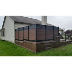 an outside view of a house with a hot tub in the grass and a fence around it