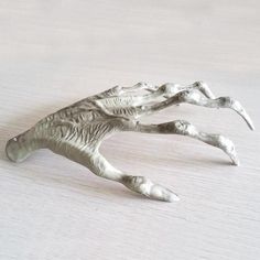 a silver figurine is laying on a white surface with one foot in the air