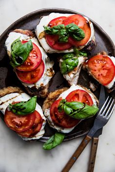 a plate with tomatoes, mozzarella and basil on it next to a fork