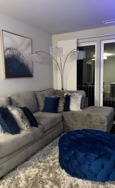 a living room filled with furniture and a blue ottoman sitting on top of a shaggy rug