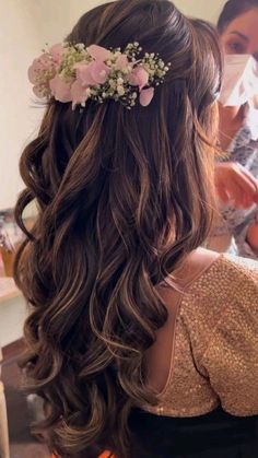 the back of a woman's head with long hair and flowers in her hair