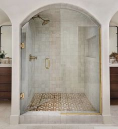 a bathroom with a walk in shower next to two sinks