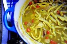 a pot filled with noodles and vegetables on top of a blue stovetop burner