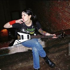 a woman sitting on the ground with an electric guitar