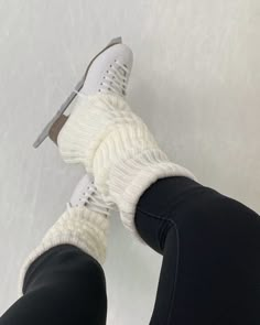 the legs and feet of a person wearing white knitted skis on a snowy surface