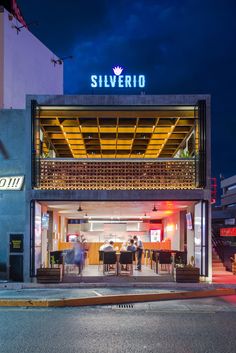 the entrance to silvero is lit up at night with people standing outside and eating