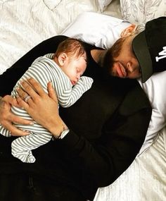 a man holding a baby sleeping on top of a bed