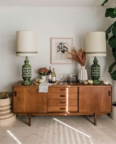 a living room filled with lots of furniture and plants on top of it's sideboard