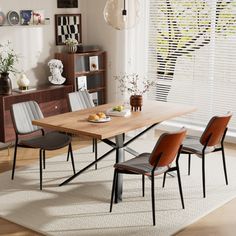 a dining room table with four chairs and a rug on the floor in front of it