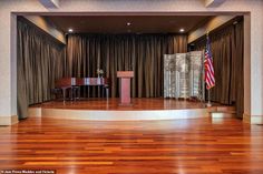 an empty stage with a podium and american flag in the center, surrounded by curtains