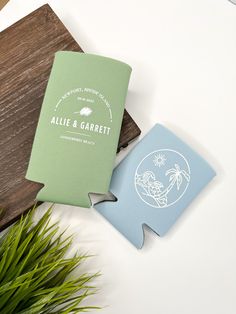 a green and blue book sitting on top of a wooden table next to a plant