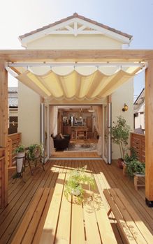 a wooden deck with an awning over it and potted plants on the side